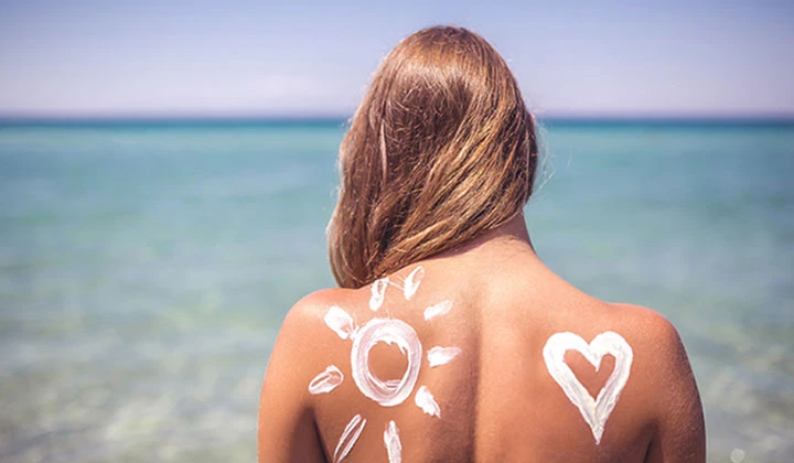 Frau mit Sonnencreme Frau mit Sonne und Herz aus Sonnencreme auf dem Rücken