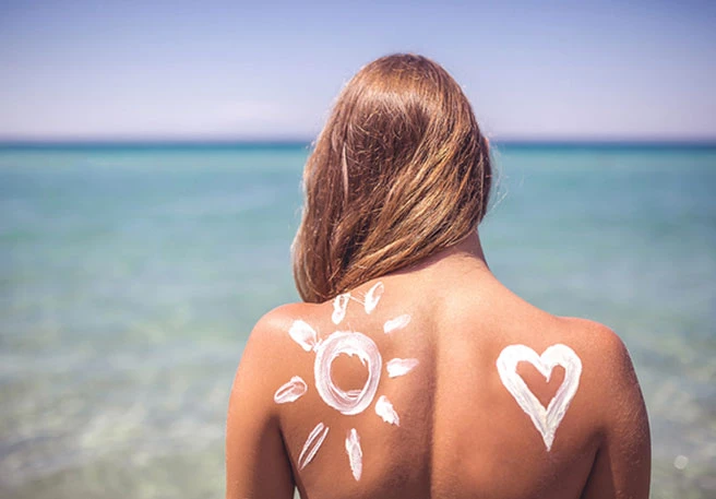 Frau mit Sonnencreme auf dem Rücken Frau mit Sonnencreme auf dem Rücken