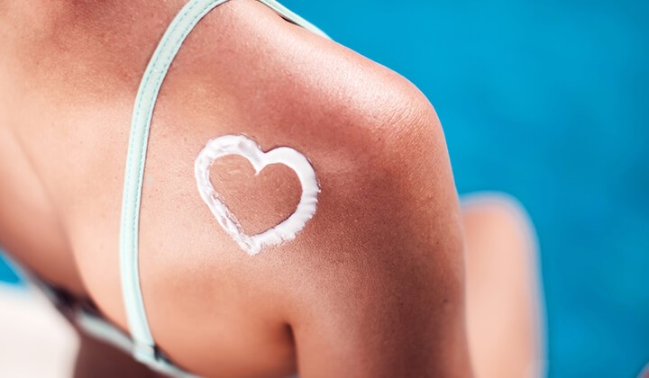 Frau mit Herz aus Sonnencreme auf der Schulter Sonnencreme & Verträglichkeit sind vielen wichtig